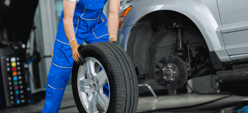 a man in blue overalls holding a tire