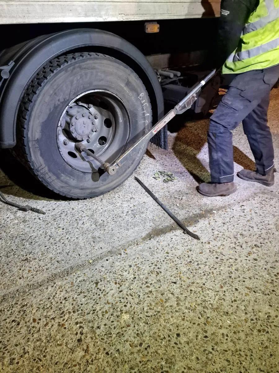 Technician in hi-vis changing an HGV wheel at night