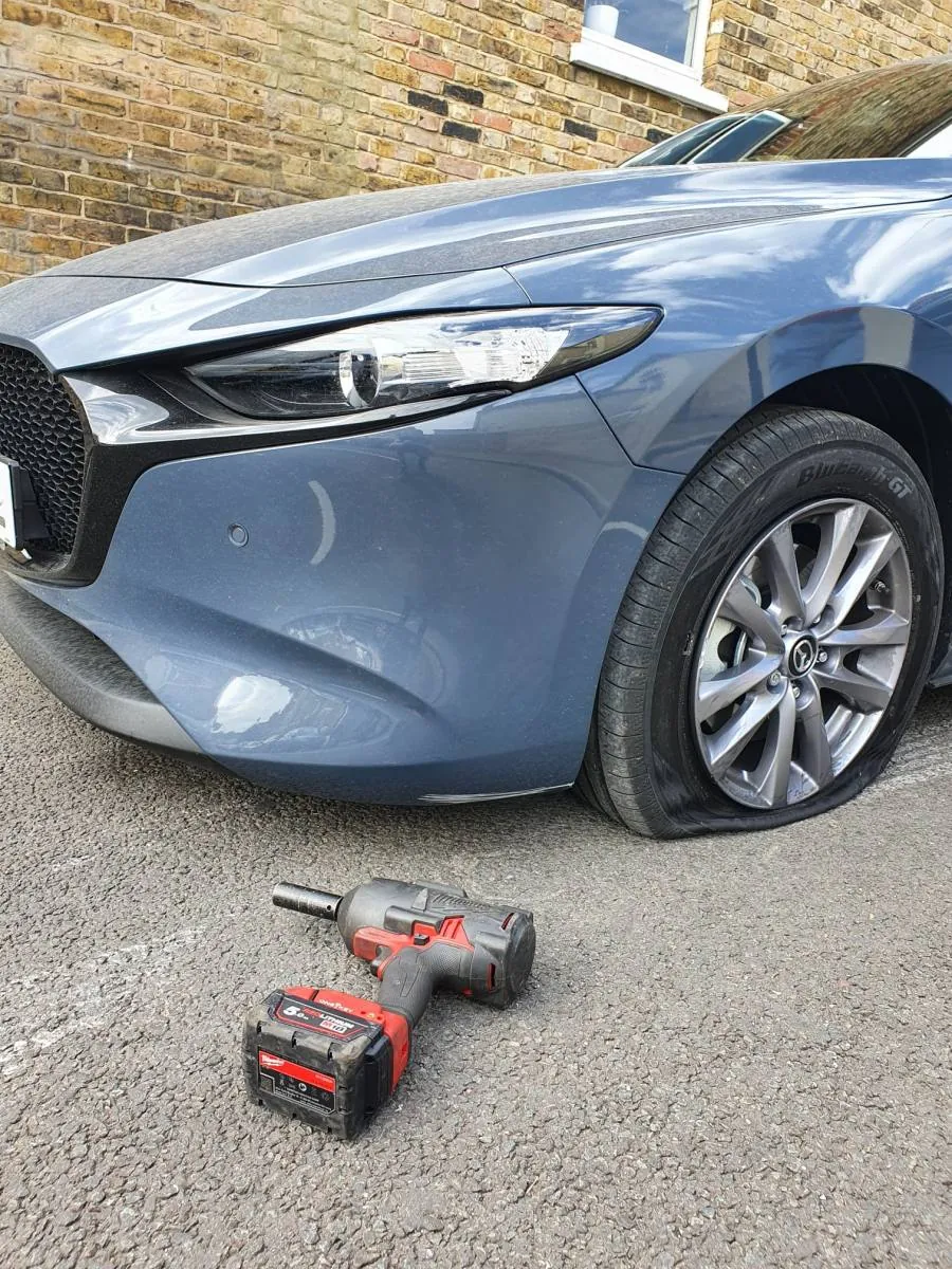 Mazda with a flat front tyre and an impact wrench ready